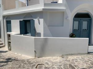 un edificio blanco con puerta azul y porche en Captain's House Plaka Milos, en Plaka Milou