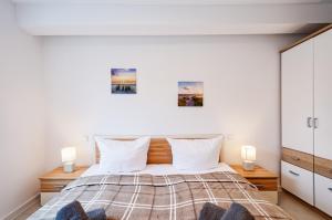 een slaapkamer met een bed met witte muren en 2 lampen bij FeWo Prora - Abendrot in Binz