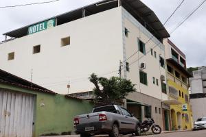 a truck parked in front of a building with a motorcycle at Hotel Pousada do Sol in Ubá