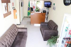 a waiting room with two couches and a tv at Hotel Pousada do Sol in Ubá