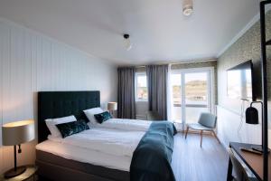 a bedroom with a large bed and a large window at Utstein Kloster Hotell in Mosterøy