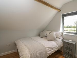 a white bedroom with a bed and a window at Kingfisher, 2 The Old Stables in Witney