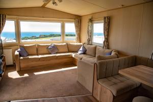 a living room with a couch and a table and windows at Devon Cliffs Holiday Home in Exmouth