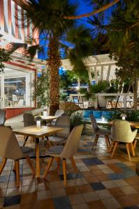 um restaurante com mesas e cadeiras e palmeiras em Blue Sea Hotel em Kamari