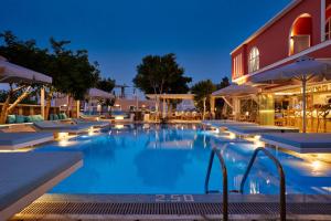 a large swimming pool with chairs and a building at Blue Sea Hotel in Kamari