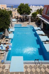 a pool with chaise lounge chairs and a hotel at Blue Sea Hotel in Kamari