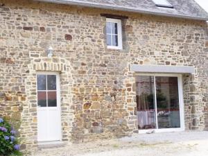 - un bâtiment en pierre avec une porte blanche et des fenêtres dans l'établissement Ecuries Leseigneur - Camping Insolites, à Bolleville