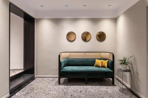 a green couch in a room with two mirrors at The Modernist Thessaloniki in Thessaloniki