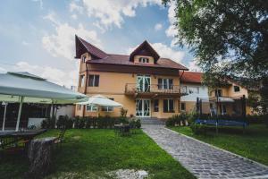 a large house with a yard with tables and chairs at La Pădure Pensiune-Restaurant in Novaci-Străini