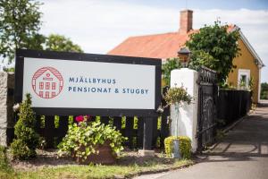 a sign in front of a house with a fence at Mjällbyhus Pensionat & Stugby in Sölvesborg