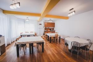 una habitación con mesas y sillas y una cocina en La Pădure Pensiune-Restaurant, en Novaci-Străini