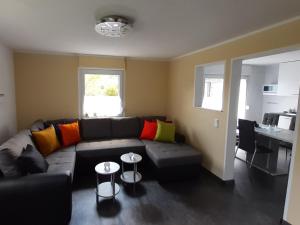 sala de estar con sofá negro y almohadas coloridas en Ferienhaus Maag, en Attendorn