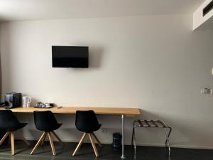 a desk with four chairs and a television on a wall at Hotel O Ieper in Ieper