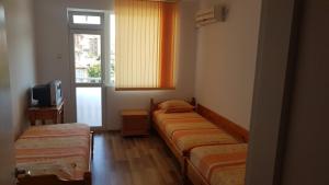 Habitación con 3 camas, TV y ventana. en Kirovi House - guest rooms, en Tsarevo