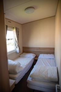 two beds in a small room with a window at Devon Cliffs Holiday Home in Exmouth