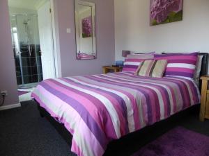 a bedroom with a large bed with purple and white stripes at Mayfields Guest House in Wokingham