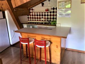 a kitchen with a counter and two red stools at Residence Trunka Lunka in Cavalese