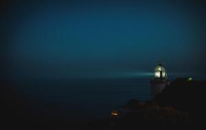 a lighthouse lit up at night in the ocean at El Far Hotel Restaurant in Llafranc