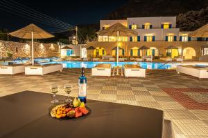 a table with a bottle of wine and a plate of fruit at Marianna Hotel in Perissa