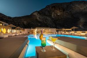a hotel pool with a drink on a table at Marianna Hotel in Perissa