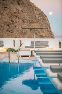 a swimming pool with an umbrella and chairs and water at Marianna Hotel in Perissa