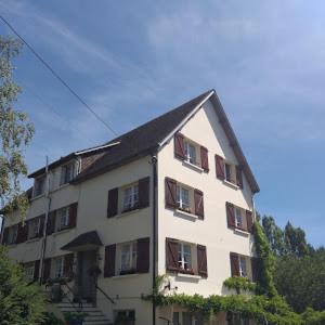 un gran edificio blanco con ventanas con persianas marrones en Lenard Charles Bed & Breakfast, en Juvigny-sous-Andaine