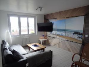 Una sala de estar con un sofá y un televisor de pantalla plana. en Gîte des Terre-Neuvas, en Fécamp