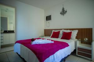 1 dormitorio con 1 cama grande con almohadas rojas en Suíte Guarapari - 3 quartos na Praia das Virtudes, en Guarapari