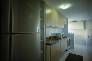 eine Küche mit einem Kühlschrank aus Edelstahl und einer Spüle in der Unterkunft Suíte Guarapari - 3 quartos na Praia das Virtudes in Guarapari