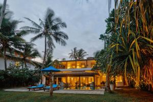 a house with palm trees in front of it at Bellini Blue in Unawatuna