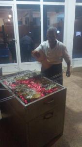 a man standing next to a grill with food at HOTEL BEACH CLUB LEGZIRA in Sidi Ifni