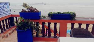 a balcony with three blue pots of plants on the beach at HOTEL BEACH CLUB LEGZIRA in Sidi Ifni