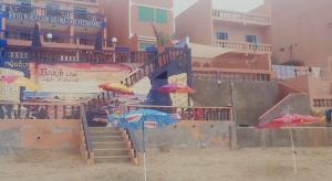 a playground with stairs and umbrellas on the beach at HOTEL BEACH CLUB LEGZIRA in Sidi Ifni
