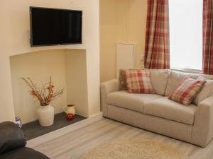 sala de estar con sofá y TV en la pared en Whitewater Cottage en Llangollen