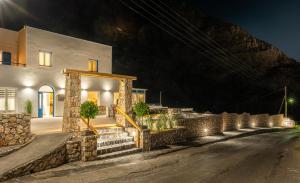 a house with a stone wall and stairs at night at Marianna Hotel in Perissa