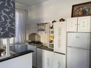 a kitchen with white cabinets and a white refrigerator at the bougainvillea house in Symi