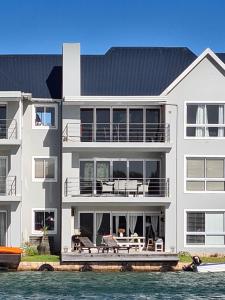 a large white house on the water next to the water at 33 Kingston Place, Marina Martinique in Jeffreys Bay