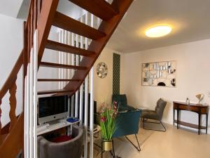 a living room with a staircase with a computer and a desk at Le Logis - lescapade-medievale Sarlat in Sarlat-la-Canéda