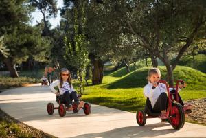 two girls riding on tricycles down a sidewalk at Maistra Select Family Hotel Amarin in Rovinj
