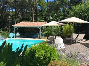 a swimming pool with two umbrellas and chairs next to it at Villa Limone, maison d'hôtes in Calenzana