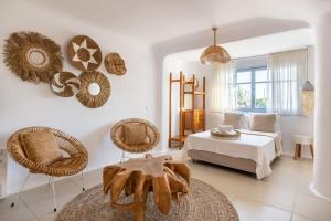 a bedroom with a bed and rattan chairs at Leno Villas Mykonos in Mýkonos City