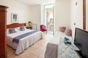 a bedroom with a bed and a tv and a couch at Hotel Mimosa in Alassio