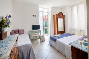 a bedroom with two beds and a desk and a television at Hotel Mimosa in Alassio