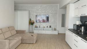 a living room with a couch and a tv on the wall at Rose By The Sea in Mamaia Nord