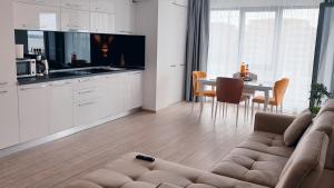 a living room with a couch and a kitchen with a table at Rose By The Sea in Mamaia Nord