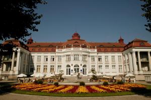 a large white building with a garden in front of it at Pension Lukas in Karlovy Vary
