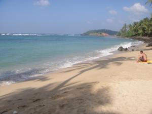 a couple of people sitting on a beach at SunRay Rest - Beach View Homestay in Mirissa