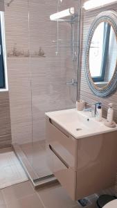 a bathroom with a sink and a shower with a mirror at Rose By The Sea in Mamaia Nord
