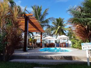 a resort with a pool and a wooden pergola at Lamares Pousada de Charme in Santa Cruz Cabrália