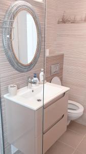 a bathroom with a sink and a mirror and a toilet at Rose By The Sea in Mamaia Nord